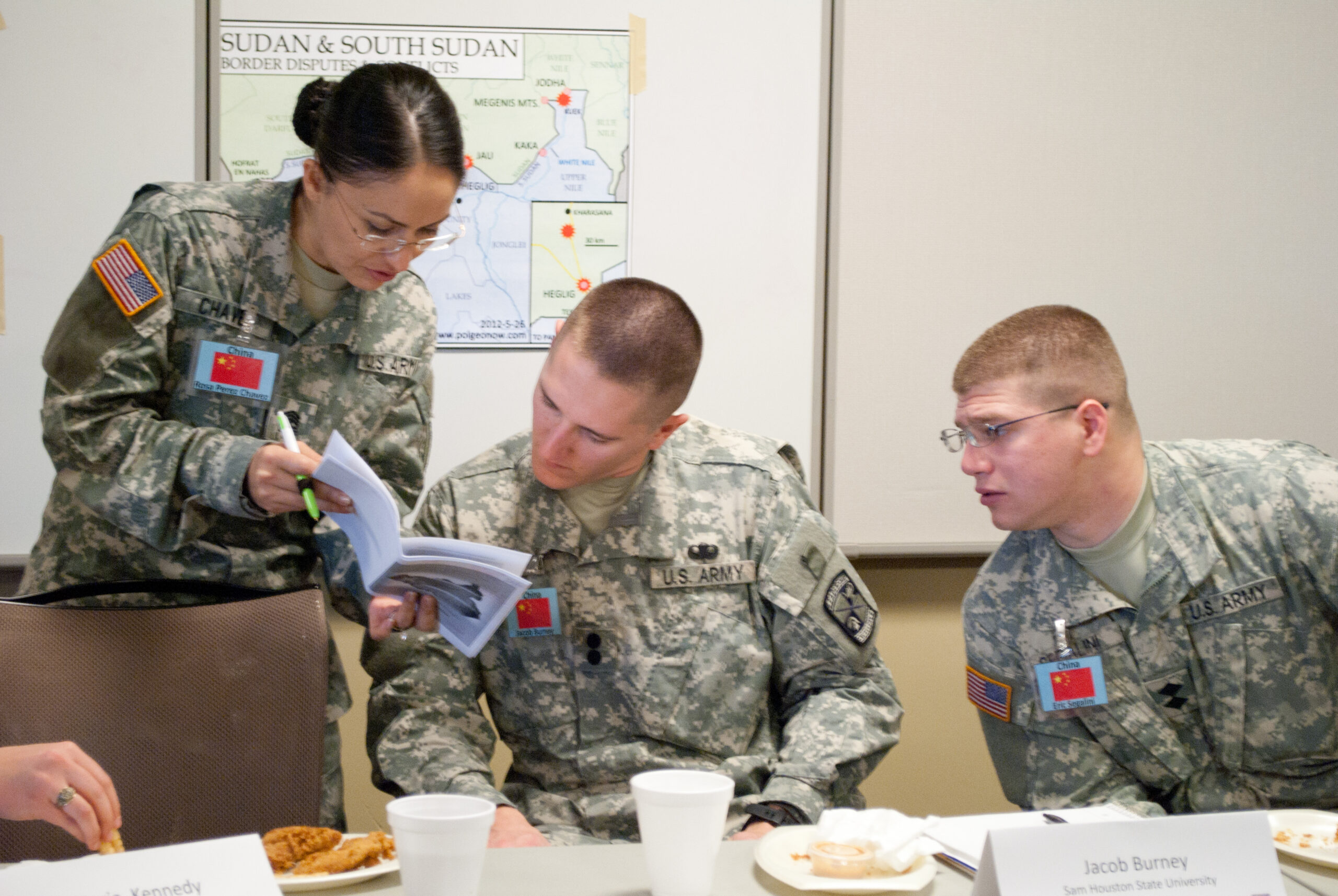 Three members seated, discussing material in a book.
